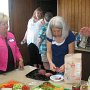Mary Shelton Madden (partially out of frame on the left),  Janet Clay Powell (pink jacket), and Claudia Robards Perney finish preparing snacks for the gathering...